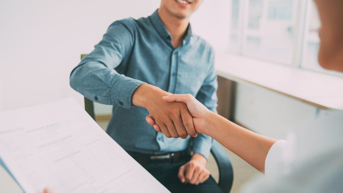 Man shaking hands while looking at resume